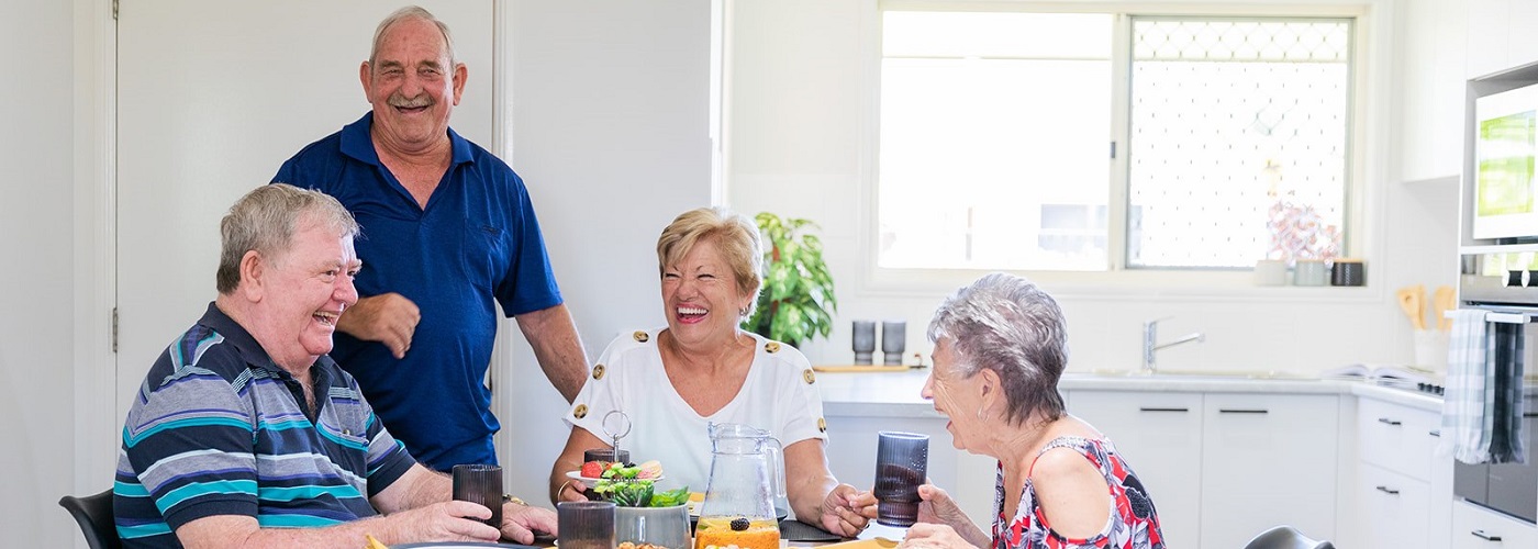 A group of seniors sitting around the coffee table laughing